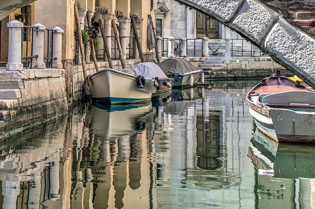 kleine, romantische Wasserstraße in Venedig mit an Hausmauer parkenden Booten
